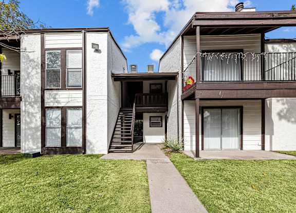 A white two-story house with a balcony on the upper floor.