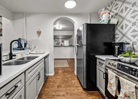 A kitchen with a black fridge and stove top oven.