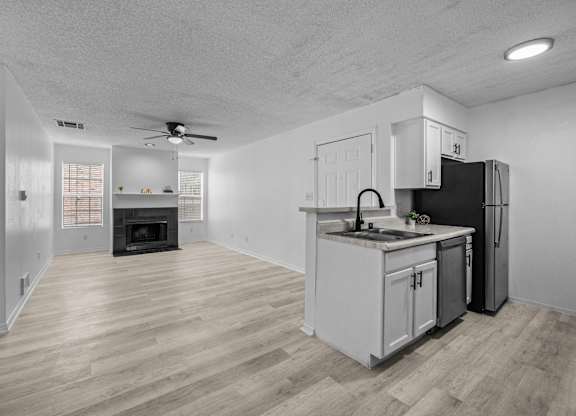 an empty living room with a kitchen with a stove and refrigerator
