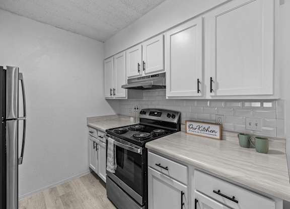 a kitchen with white cabinets and a stove and a refrigerator