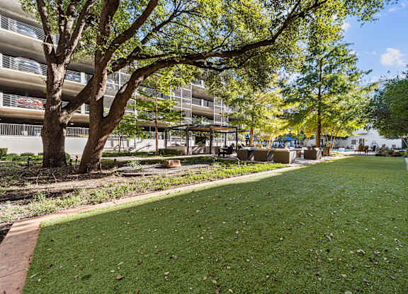 a park with grass and trees in front of a building