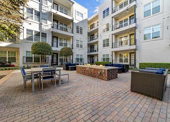 a brick patio with a fire pit in front of an apartment building