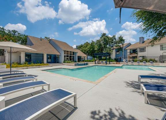 A sunny day at the pool with lounge chairs and a clear blue sky.