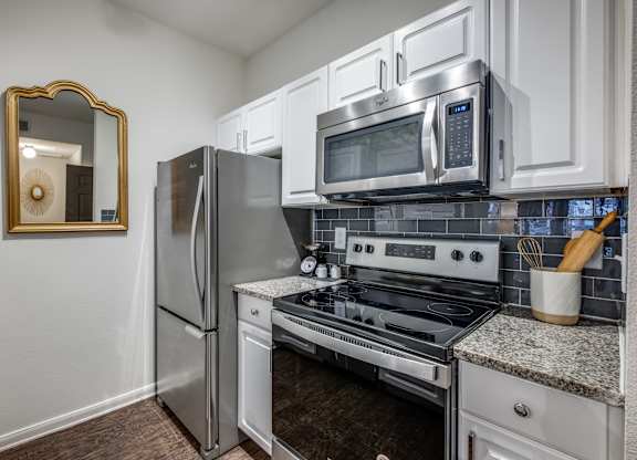 an updated kitchen with stainless steel appliances and white cabinets