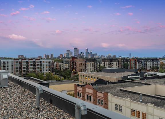A train track with a train on it in the foreground with a city skyline in the background.