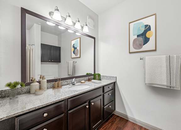 A bathroom with a large mirror, a sink, and a towel rack.