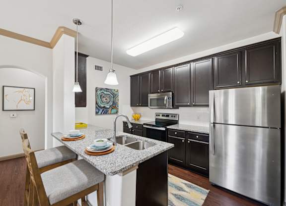 A kitchen with a stainless steel refrigerator and a dining table with chairs.