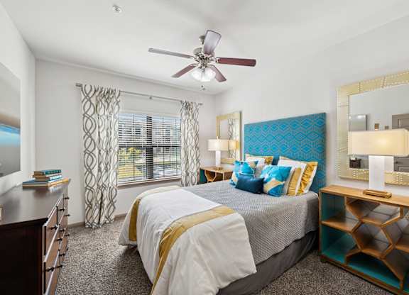 A bedroom with a large bed and a ceiling fan.