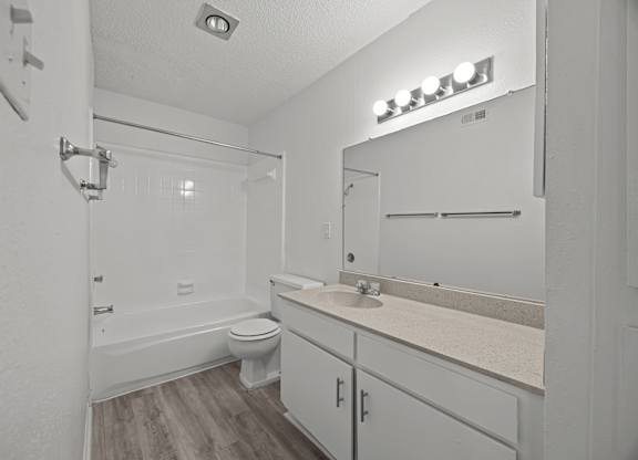 A white bathroom with a toilet, sink, and mirror.