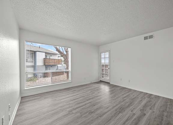 Empty room with wooden flooring and a window showing an outdoor view.