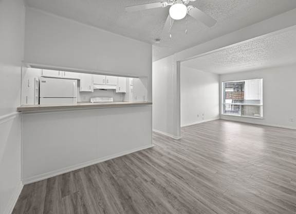 A spacious room with a kitchen area and a ceiling fan.