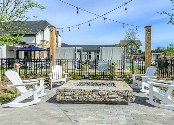 A patio with white chairs and a fire pit.