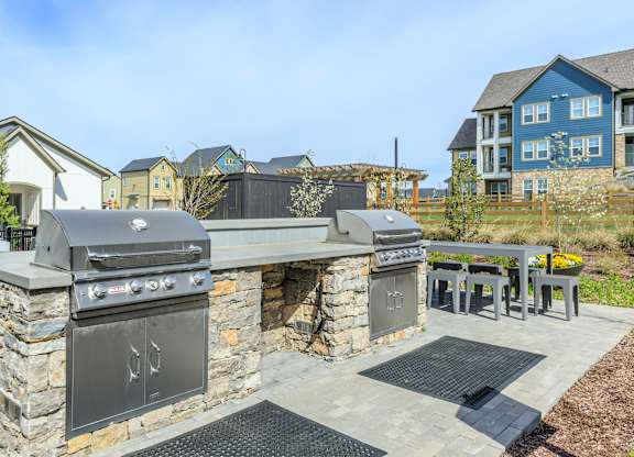 A stone outdoor kitchen with a grill and sink.