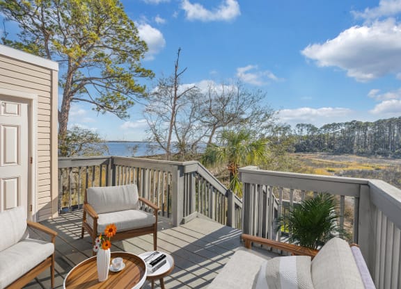 a deck with two chairs and a table overlooking a body of water