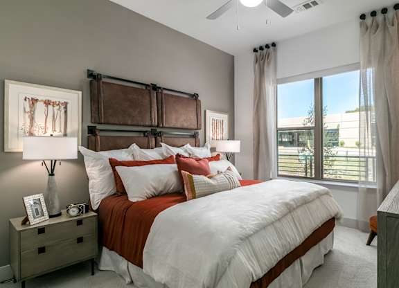 A bedroom with a large bed and a window overlooking a building.