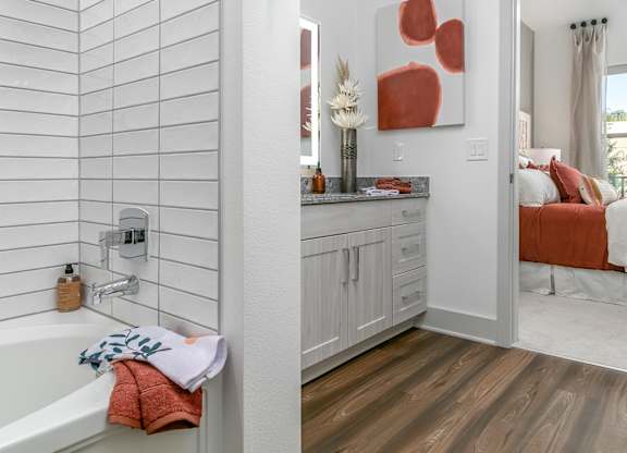 A bathroom with a white tub and a wooden floor.