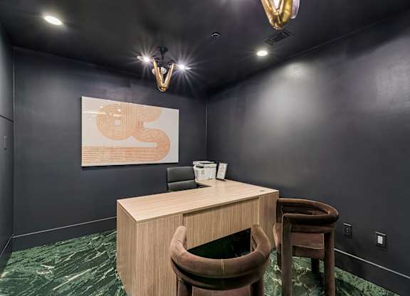 A room with a desk and chair and a painting on the wall.