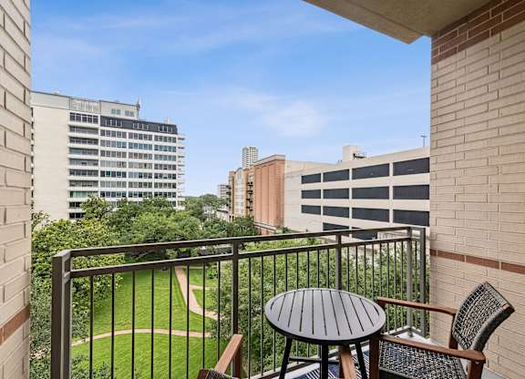 A balcony with a table and chairs overlooking a green area.