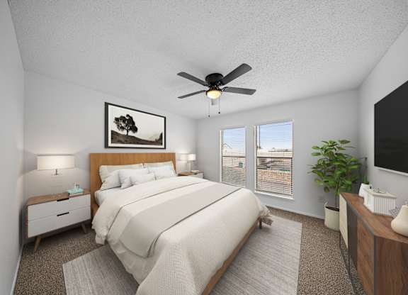 A bedroom with a large bed, a ceiling fan, and a painting on the wall.