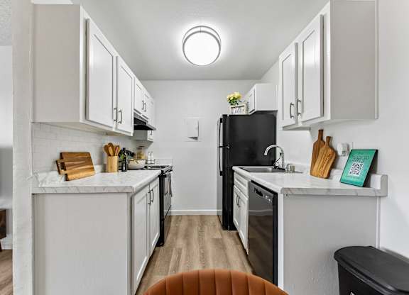 A kitchen with white cabinets and a black refrigerator.
