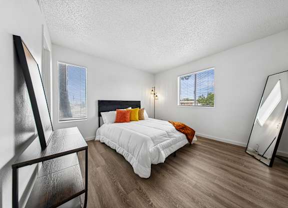 A bedroom with a bed, a chair, and a mirror.