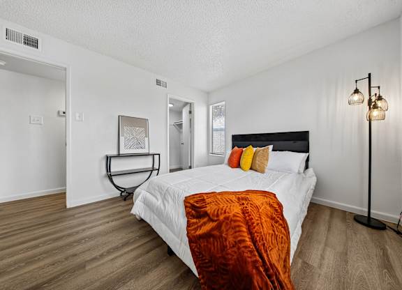 A bedroom with a bed, a lamp, and a chair.