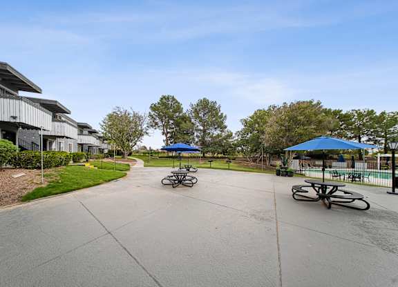 A parking lot with a few cars and a blue umbrella.