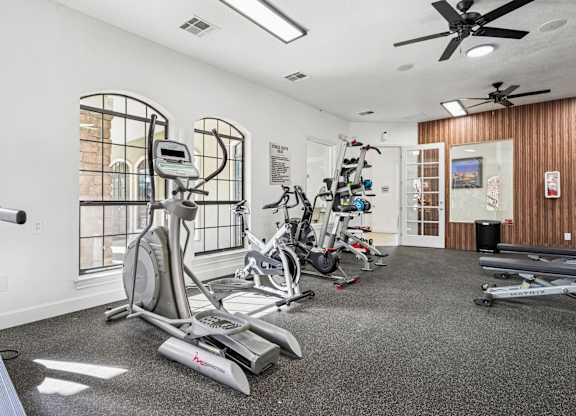 A spacious gym with a variety of exercise equipment including treadmills, stationary bikes, and elliptical machines.