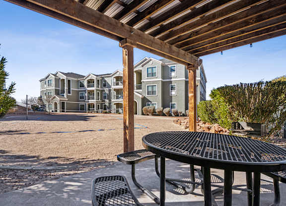 A patio with a table and chairs is in front of a large building.