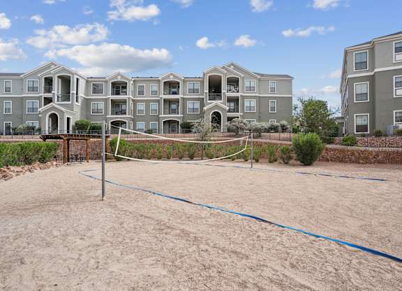 A sand volleyball court in front of apartment buildings.