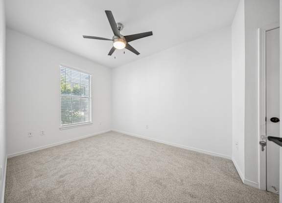 A room with a ceiling fan and a window with blinds.
