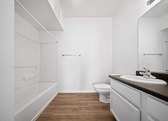 A white bathroom with a toilet, sink, and mirror.