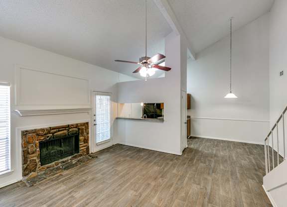 an empty living room with a fireplace and a ceiling fan