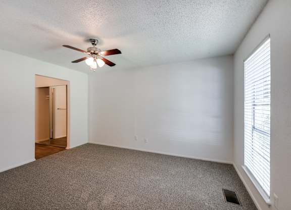 the living room of an empty house with a ceiling fan