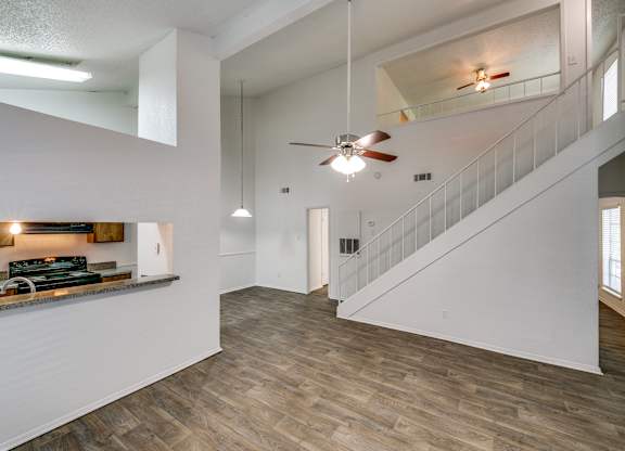 the living room and entryway of a house with white walls and a ceiling fan