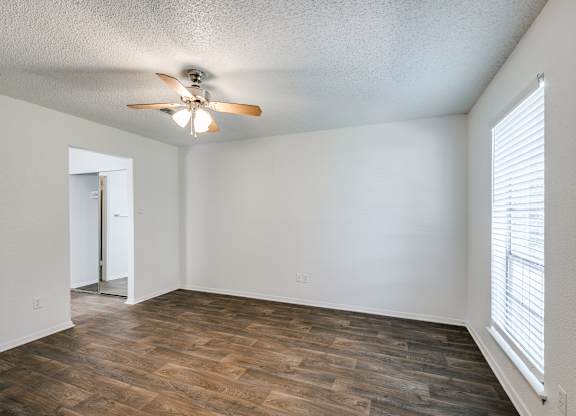 an empty living room with a ceiling fan and a window