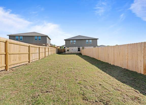 a backyard with a wooden fence and two houses in the background