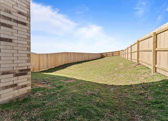 a backyard with a wooden fence and grass