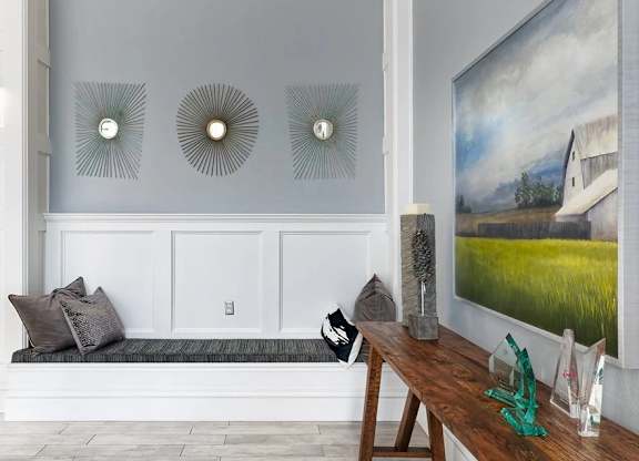 A room with a bench, a table, and three wall decorations.