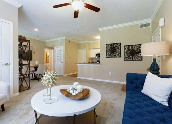 A living room with a white ceiling fan and a white coffee table with a star decoration and a plate of cookies.
