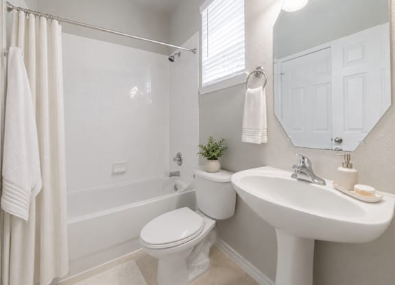 A white bathroom with a toilet, sink, and bathtub.
