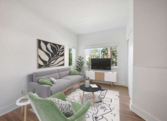 A living room with a grey couch, a green chair, and a painting on the wall.