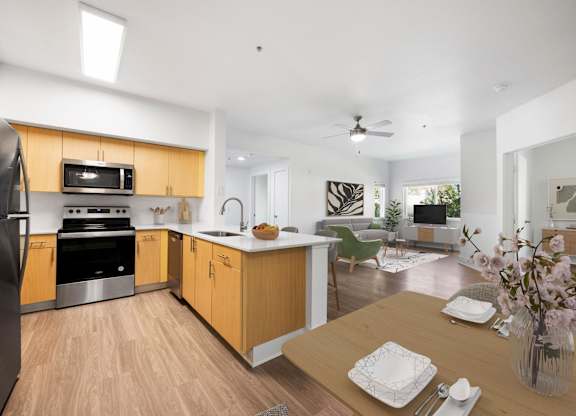 A modern kitchen with wooden cabinets and a dining table set for two.