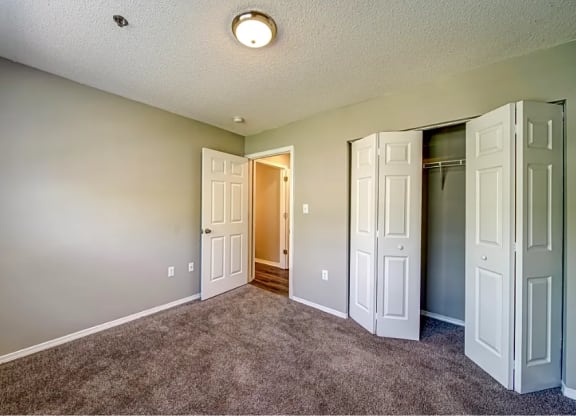 a empty room with closet doors and a door to a hallway