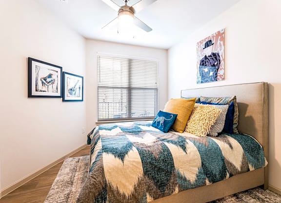 A bedroom with a bed, pillows, and pictures on the wall.