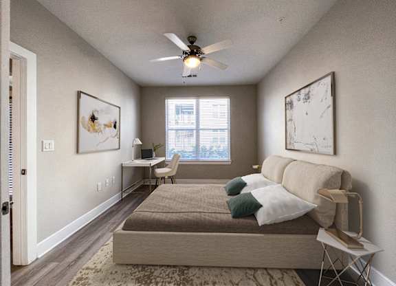 A bedroom with a bed, a desk, and a ceiling fan.