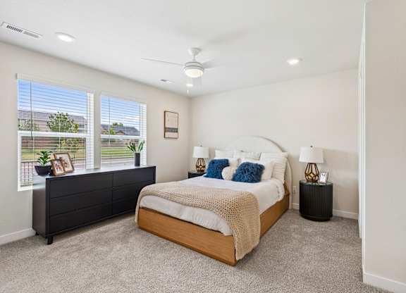 A bedroom with a large bed and a window with a view of a fence and trees.