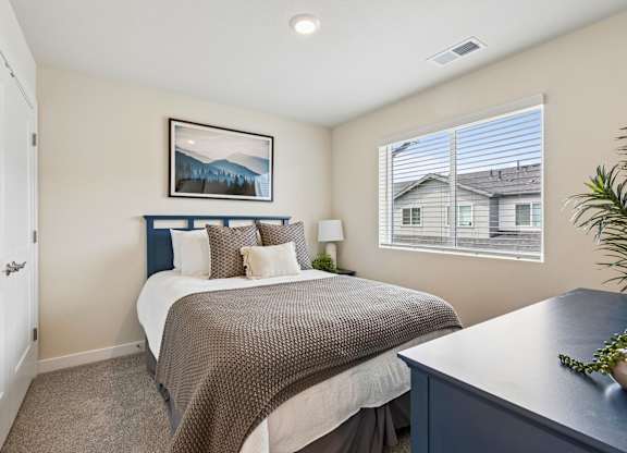 A bedroom with a bed, nightstand, and a painting on the wall.