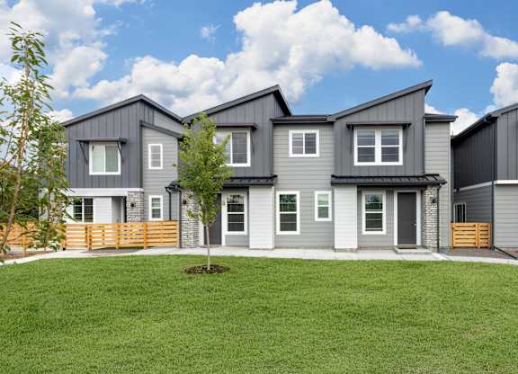 A row of modern houses with grey exteriors and wooden fences.