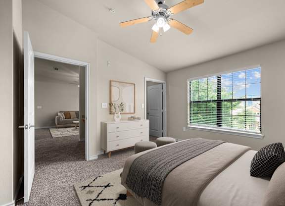 A bedroom with a large bed and a ceiling fan.